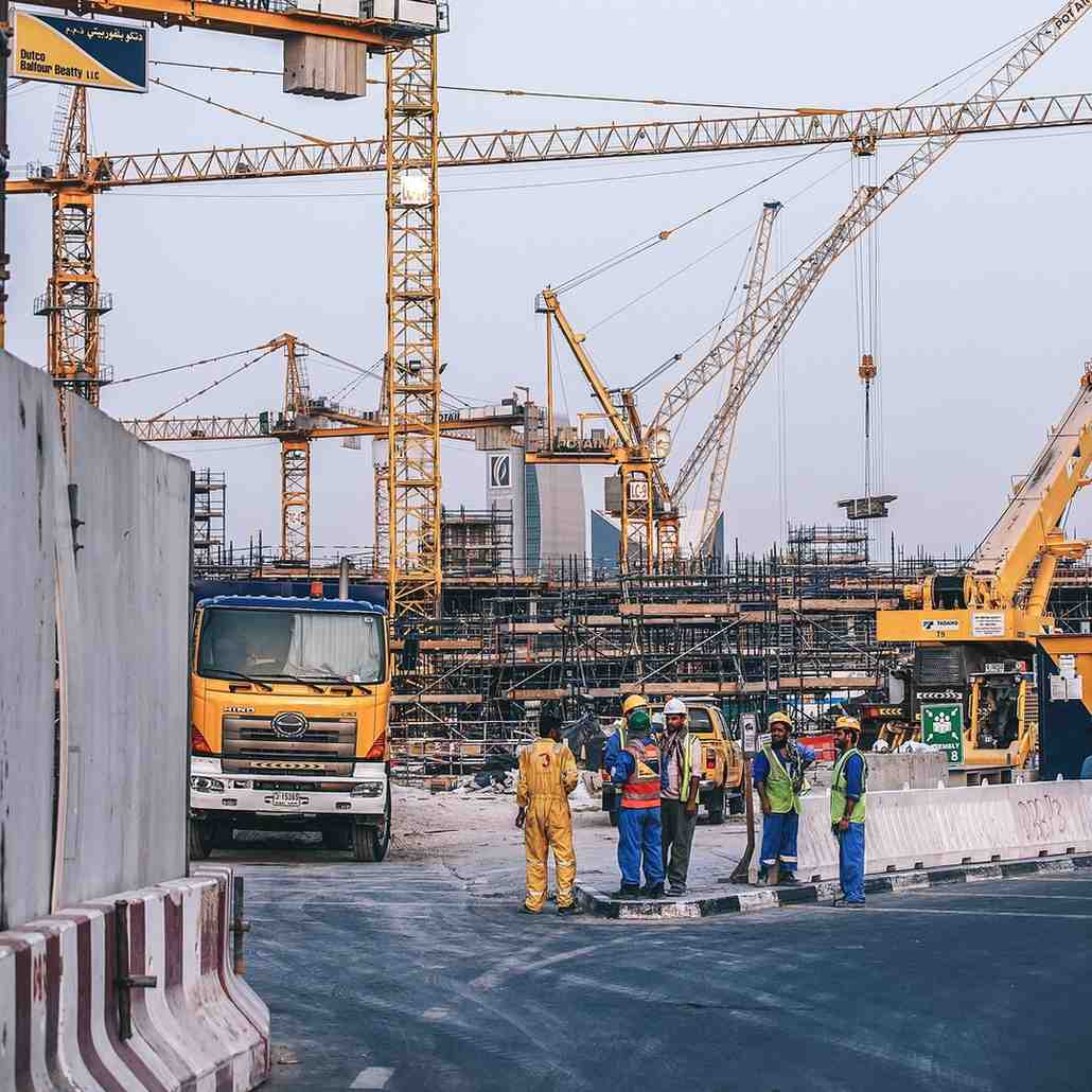 Construction workers gathered near a yellow truck and cranes